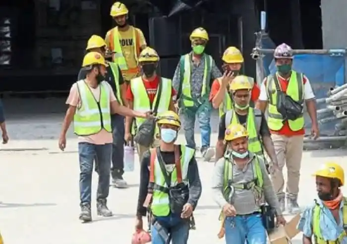 Construction workers in safety gear walking at a construction site. Channel i News - চ্যানেল আই নিউজ