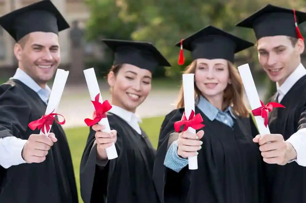 Students in graduation gowns holding diplomas at outdoor ceremony. Channel i News - চ্যানেল আই নিউজ